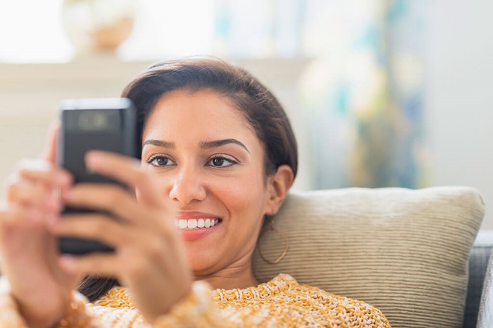 woman using cell phone on sofa