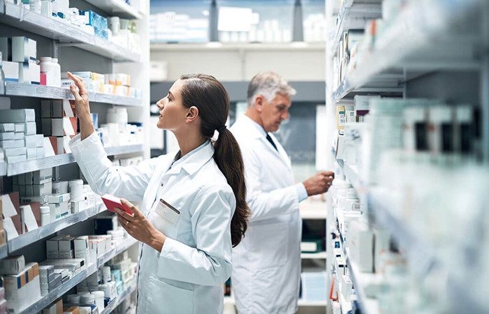 Two pharmacists checking products on dispensary shelves